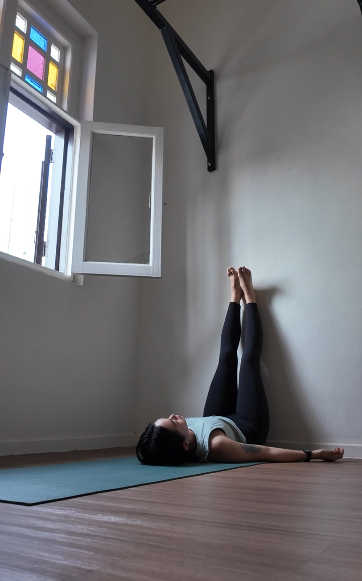 Woman standing from her desk pressing a hand into her stiff lower back and hips